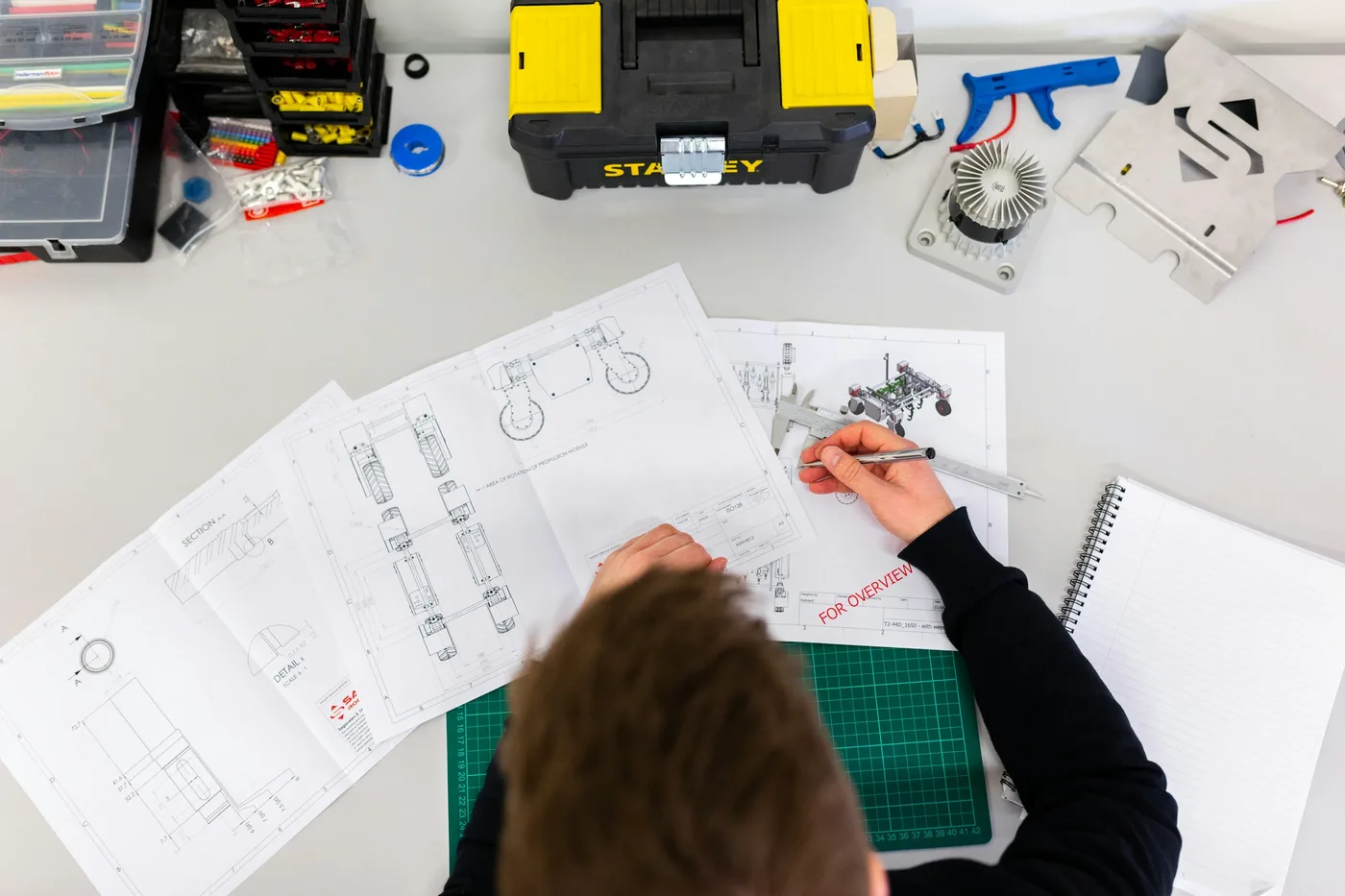Engineer measuring technical drawings at a workbench